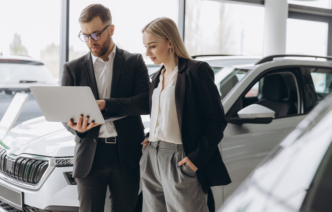 due persone che consultano il contratto di un auto davanti a un pc